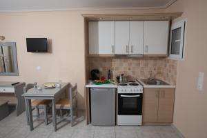 a kitchen with white cabinets and a small table at eleni studios in Vlachata
