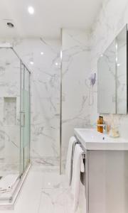 La salle de bains blanche est pourvue d'une douche et d'un lavabo. dans l'établissement 44-COSY FLAT MONTORGUEIL (2CHENIER), à Paris