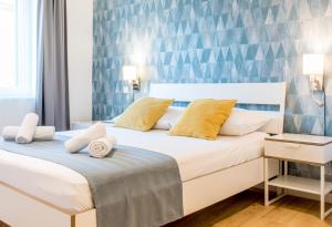 een slaapkamer met een groot wit bed met gele kussens bij Wind Rose Split in Split