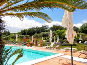 a pool with umbrellas and chairs next to a resort at Agriturismo Rosa Antica in Monte San Vito