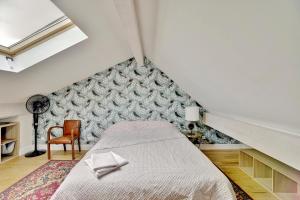 a attic bedroom with a bed and a chair at House Perigourdine ex former diligence relay in Falgueyrat +54 photos