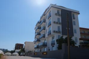 een groot wit appartementencomplex op een parkeerplaats bij YILDIZ APART in Demre
