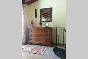 Cette chambre comprend une commode en bois et un miroir. dans l'établissement Una piccola casa confortevole, à Campobello di Licata