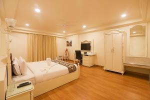 斋浦尔Hotel Magenta Jaipur的一间卧室，里面有一张床、一张桌子和一台电视。