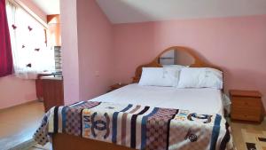 ein Schlafzimmer mit einem großen Bett in einem rosa Zimmer in der Unterkunft Guest House Pogradeci in Pogradec