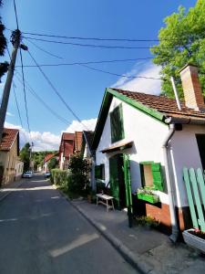 una casa blanca con puertas verdes y un banco en una calle en Zebegényi Présház, en Zebegény