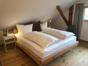 1 dormitorio con 1 cama grande con sábanas y almohadas blancas en mama käthe - Apartments, en Nenzing