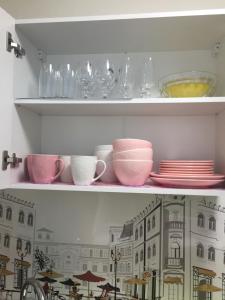 a shelf with plates and bowls and glasses on it at Karja 5 Apartment in Narva-Jõesuu