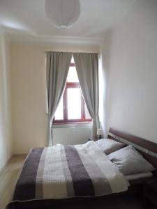una camera da letto con un letto con una coperta scozzese e una finestra di M10 Old Town Apartments Kosice a Košice