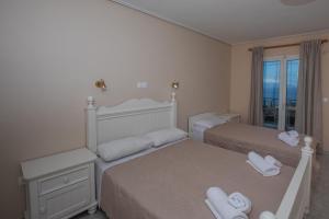 a white bedroom with two beds and a window at eleni studios in Vlachata