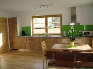 a kitchen with a wooden table and a green wall at Haus Alexander in Pfunds