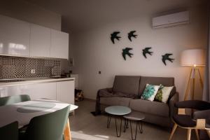 sala de estar con sofá y pájaros en la pared en Apartamentos Turísticos Huerto El Horno, en Torremenga