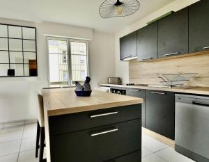 a kitchen with black cabinets and a wooden counter top at Appartement des Arts in Deauville