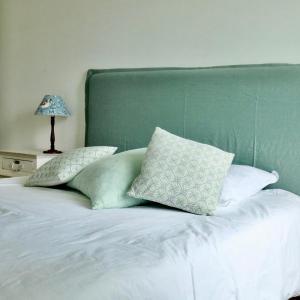 uma cama com almofadas brancas e uma cabeceira verde em Appartement des Arts em Deauville