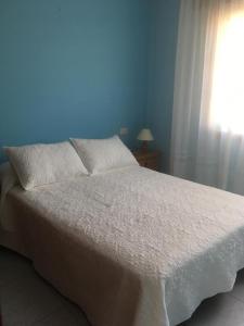 a bedroom with a white bed with a window at Apartamentos baltar sanxenxo 1 in Sanxenxo