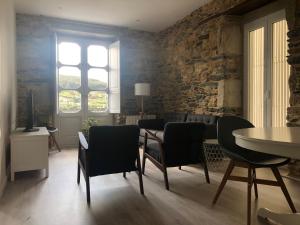 ein Wohnzimmer mit einem Tisch, Stühlen und einer Steinmauer in der Unterkunft Noray Apartamentos Viveiro in Viveiro