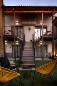 un edificio con 2 sillas y una escalera en Apartamentos Turísticos Huerto El Horno en Torremenga
