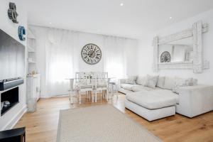 a living room with white furniture and a clock on the wall at The white home near Kensington high st in London