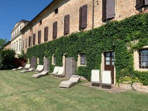 uma fila de cadeiras sentadas fora de um edifício em Corte degli Angeli Società Agricola e Agrituristica em Busseto