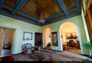 a living room with a ceiling and a table and chairs at Pałac Paprotno in Karnitz