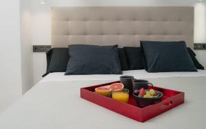 bandeja roja con fruta y bebidas en una cama en El Rincón de Eva en Salamanca