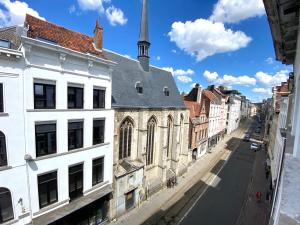 una calle de la ciudad con edificios blancos y una iglesia en BONJOUR Apartments Сentre 3, en Amberes