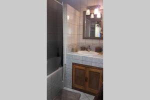 a bathroom with a sink and a tub and a mirror at Joli loft dans village pittoresque in Péret +25 photos