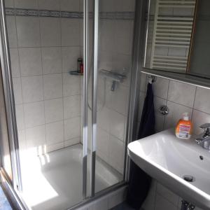 una ducha con una puerta de cristal junto a un lavabo y una bañera en Ferienhaushälfte Domeyer Midlum, en Midlum 2 fotos más