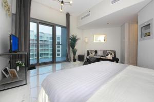 a bedroom with a large white bed and a tv at SHH - Furnished Studio in MAG 5, Dubai South Near to Expo 2020 in Dubai