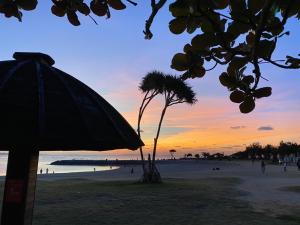 einen Sonnenuntergang am Strand mit einer Palme in der Unterkunft サンセットビーチホテル in Chatan