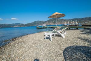 twee stoelen en een parasol op een strand bij Balalayka Butik Otel in Mugla