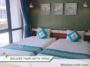 FLORA Hotel Phu Quoc في فو كووك: سريرين في غرفة مع وسائد زرقاء وبيضاء