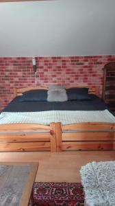 uma cama de madeira num quarto com uma parede de tijolos em Apart - House em Sandomierz