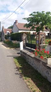 uma casa com uma cerca e flores ao lado de uma rua em A La Chataigneraie em Mosnes