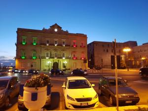 a white car parked in front of a building with green lights at Philos - Appartements & Rooms in Taranto