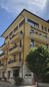 un edificio amarillo con balcones y un árbol en Hotel Villa Venezia, en Grado