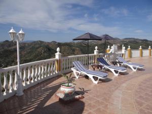 un patio con sillas y sombrillas en el balcón en B&B Casa Sarandy - Casita Mayo, en Almogía