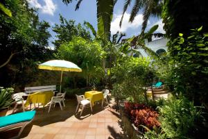 a patio with tables and chairs and an umbrella at Hotel Villa Angelica in Ischia