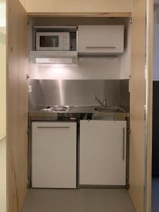 uma pequena cozinha com armários brancos e um micro-ondas em Ambiance bois - 2 appartements em Vannes