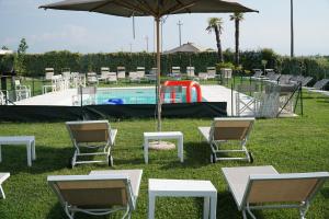 um grupo de cadeiras e um guarda-sol junto a uma piscina em B&B Eldorado em Sommacampagna