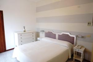 a bedroom with a white bed and a white dresser at Hotel Atlantico in Castiglioncello