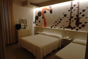 a hotel room with two beds and a wall with a mural at Hotel Atlantico in Castiglioncello