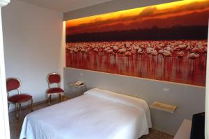 a bedroom with a painting of birds on the wall at Hotel Atlantico in Castiglioncello