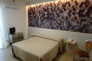 a bedroom with a bed and a painting on the wall at Hotel Atlantico in Castiglioncello
