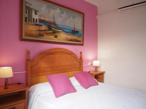 a bedroom with a bed with two purple pillows at Chalet Sa Marina in Port d'Alcudia