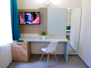 a room with a chair and a desk with a television at Hotel Lotos in Kiten