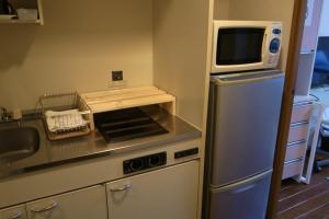 uma cozinha com um micro-ondas em cima de um frigorífico em KYOTO SANJO Inn 京都三条イン em Quioto