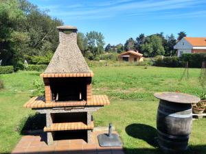 una pequeña barbacoa de ladrillo en un patio con un campo en Les Viesques en Colunga