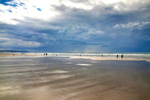 un groupe de personnes marchant sur la plage dans l'établissement Le Yearling, à Deauville