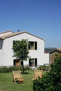 two lawn chairs in front of a white house at Agriturismo Parmoleto in Montenero